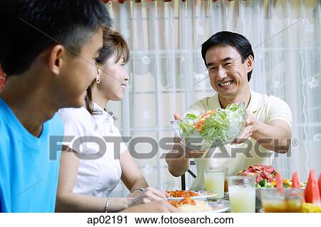 Father passing salad bowl to family members View Large Photo Image Stock Image - Father passing salad bowl to family members . Fotosearch