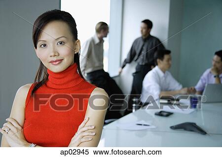 Female executive, arms crossed, looking at camera, people in the background View Large Photo Image Stock Photography - Female executive, arms crossed, looking at camera, people in the background. Fotosearch