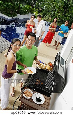 Stock Photograph - Friends at barbeque party, smiling at camera . Fotosearch
