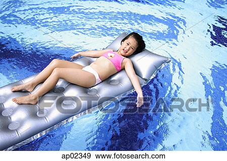 Girl lying on inflatable bed in swimming pool View Large Photo Image Stock Photo - Girl lying on inflatable bed in swimming pool . Fotosearch