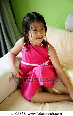 Girl sitting on sofa, smiling View Large Photo Image Stock Photo - Girl sitting on sofa, smiling . Fotosearch