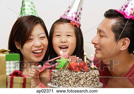 Girl with birthday cake, parents on either side smiling View Large Photo Image Stock Image - Girl with birthday cake, parents on either side smiling . Fotosearch