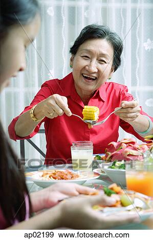 Stock Photo - Grandmother and granddaughter at dining table, eating . Fotosearch