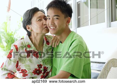 Grandmother giving grandson a kiss on the cheek View Large Photo Image Stock Photo - Grandmother giving grandson a kiss on the cheek . Fotosearch