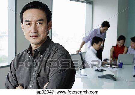 Male executive, looking at camera, people in the background View Large Photo Image Stock Photo - Male executive, looking at camera, people in the background . Fotosearch