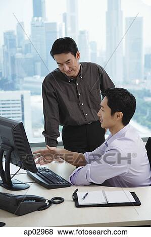 Male executives in office, having a discussion, looking at computer View Large Photo Image Stock Photo - Male executives in office, having a discussion, looking at computer . Fotosearch
