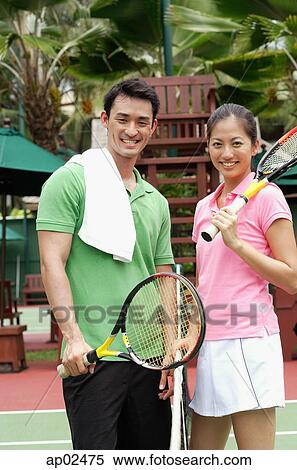 Man and women standing on tennis court, smiling at camera View Large Photo Image Stock Photography - Man and women standing on tennis court, smiling at camera . Fotosearch