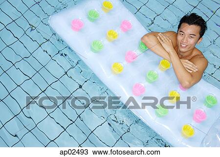 Stock Image - Man in swimming pool, leaning arms on pool raft . Fotosearch