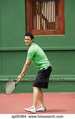 Picture - Man serving a game of tennis on tennis courts . Fotosearch