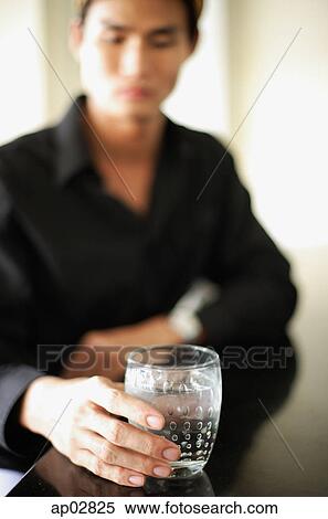 Man sitting at counter, holding drink View Large Photo Image Stock Photography - Man sitting at counter, holding drink . Fotosearch