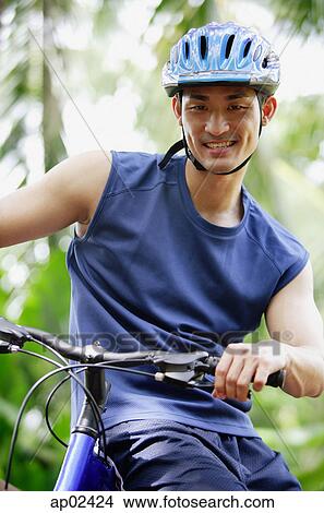 Man sitting on bicycle, looking at camera View Large Photo Image Picture - Man sitting on bicycle, looking at camera . Fotosearch