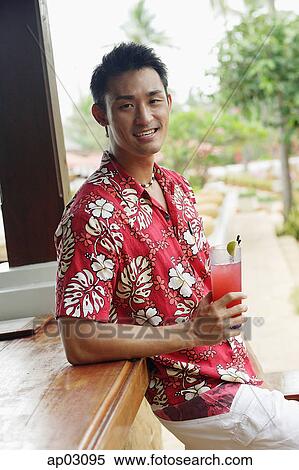 Man standing at bar counter, holding drink, smiling at camera View Large Photo Image Stock Photography - Man standing at bar counter, holding drink, smiling at camera . Fotosearch