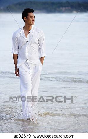 Man walking on beach, hand in pocket, ankle deep in water View Large Photo Image Stock Photo - Man walking on beach, hand in pocket, ankle deep in water . Fotosearch