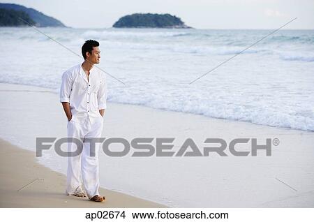 Man walking on beach, hands in pocket View Large Photo Image Picture - Man walking on beach, hands in pocket . Fotosearch