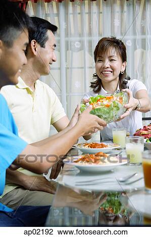 Mother passing salad bowl to family members View Large Photo Image Stock Image - Mother passing salad bowl to family members . Fotosearch