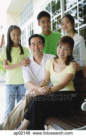 Stock Photograph - Parents with three children, smiling at camera. Fotosearch