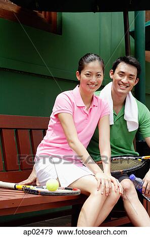 Portrait of Man and Woman sitting on bench with tennis racket, looking at camera and smiling View Large Photo Image Stock Photo - Portrait of Man and Woman sitting on bench with tennis racket, looking at camera and smiling . Fotosearch