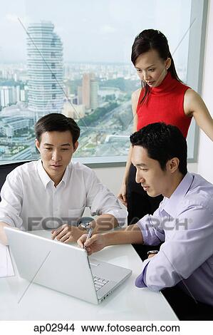 Picture - Three executives looking at laptop. Fotosearch