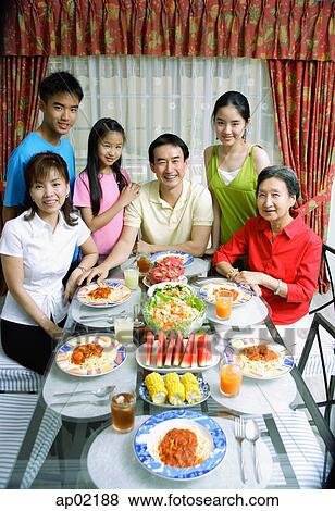 Stock Photo - Three generation family around dining table, portrait . Fotosearch