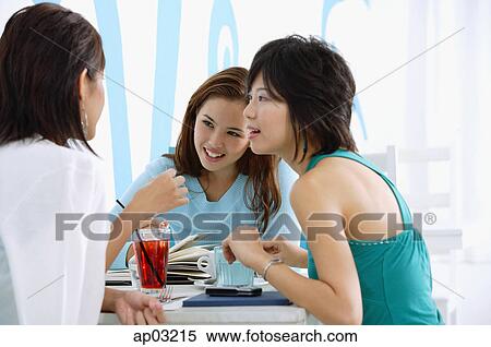 Stock Photography - Three young women sitting in cafe, talking . Fotosearch