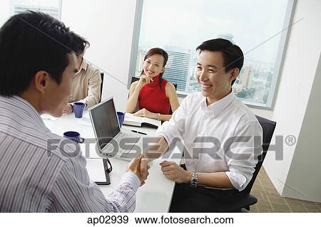 Two businessmen exchanging business cards, woman looking at them View Large Photo Image Stock Photo - Two businessmen exchanging business cards, woman looking at them . Fotosearch