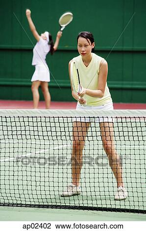 Stock Image - Two women playing a game of tennis . Fotosearch