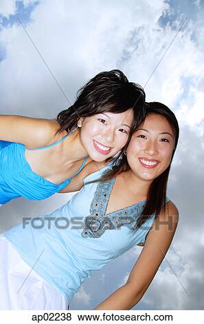 Two women smiling at camera, low angle view View Large Photo Image Stock Photo - Two women smiling at camera, low angle view . Fotosearch