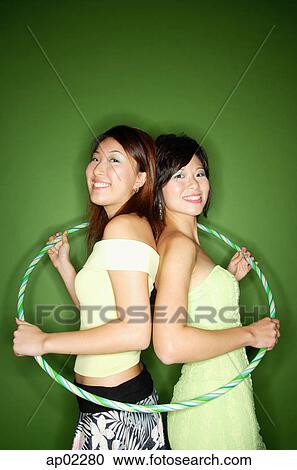 Two women standing back to back, hoola hoop around them View Large Photo Image Stock Image - Two women standing back to back, hoola hoop around them . Fotosearch