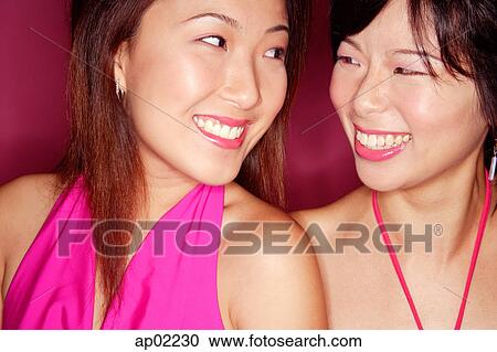 Stock Image - Two young women side by side smiling at each other . Fotosearch
