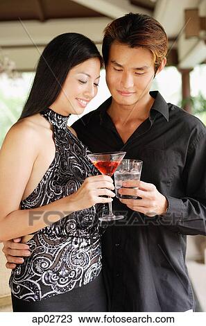 Well dressed couple, holding drinks, toasting View Large Photo Image Stock Image - Well dressed couple, holding drinks, toasting . Fotosearch
