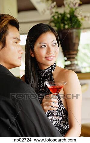 Well dressed couple, looking away, woman holding a drink View Large Photo Image Picture - Well dressed couple, looking away, woman holding a drink . Fotosearch
