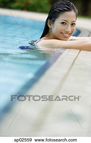 Woman at the edge of swimming pool, smiling View Large Photo Image Stock Photo - Woman at the edge of swimming pool, smiling . Fotosearch