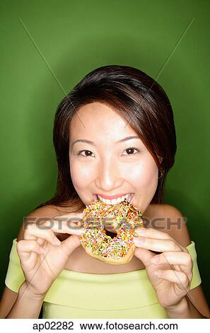 Woman biting into donut, looking at camera View Large Photo Image Stock Image - Woman biting into donut, looking at camera . Fotosearch