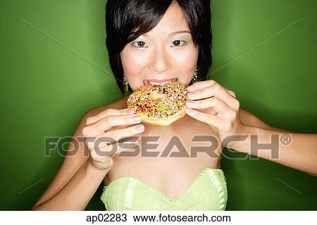 Woman biting into donut View Large Photo Image Stock Image - Woman biting into donut. Fotosearch