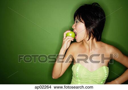 Woman biting into green apple, side view View Large Photo Image Picture - Woman biting into green apple, side view. Fotosearch