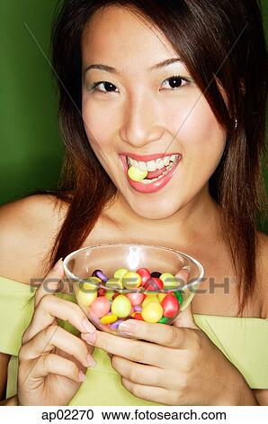 Woman eating candy and holding candy bowl View Large Photo Image Stock Image - Woman eating candy and holding candy bowl . Fotosearch