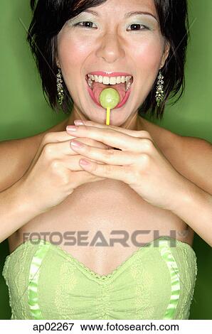 Stock Photo - Woman eating lollipop. Fotosearch