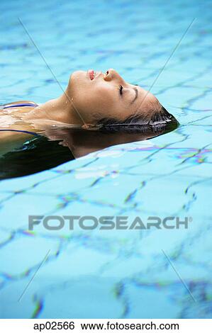 Woman floating in swimming pool View Large Photo Image Stock Photograph - Woman floating in swimming pool . Fotosearch