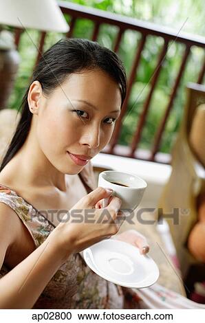 Stock Image - Woman holding cup and saucer, looking at camera . Fotosearch