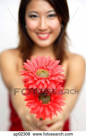 Stock Photo - Woman holding flowers towards camera, smiling . Fotosearch