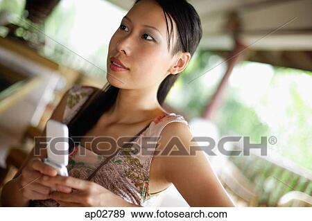 Woman holding mobile phone, looking away View Large Photo Image Stock Photo - Woman holding mobile phone, looking away . Fotosearch