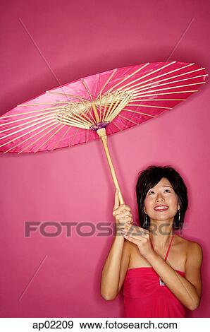 Woman holding pink umbrella, looking up View Large Photo Image Stock Photo - Woman holding pink umbrella, looking up . Fotosearch