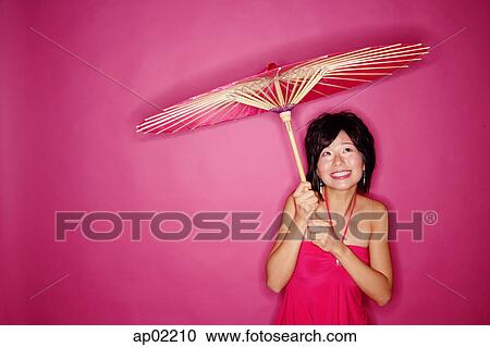 Woman holding umbrella, standing against pink background View Large Photo Image Stock Image - Woman holding umbrella, standing against pink background . Fotosearch