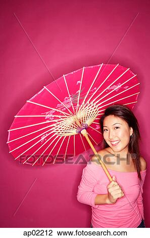Woman holding umbrella, wearing pink top, standing against pink background View Large Photo Image Stock Image - Woman holding umbrella, wearing pink top, standing against pink background . Fotosearch