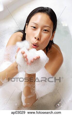 Woman in bathtub, blowing soap suds at camera View Large Photo Image Stock Photo - Woman in bathtub, blowing soap suds at camera . Fotosearch