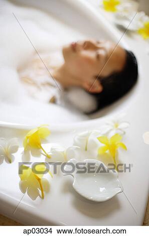 Woman in bathtub, focus on the flowers at the edge of tub View Large Photo Image Picture - Woman in bathtub, focus on the flowers at the edge of tub. Fotosearch