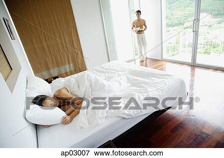 Woman in bedroom, sleeping, man walking in with tray View Large Photo Image Stock Photo - Woman in bedroom, sleeping, man walking in with tray. Fotosearch