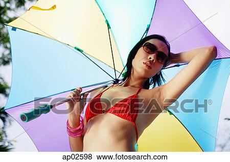 Woman in bikini and sunglasses, holding umbrella View Large Photo Image Stock Photo - Woman in bikini and sunglasses, holding umbrella. Fotosearch