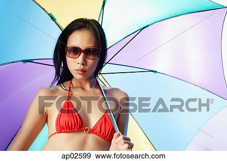 Woman in bikini and sunglasses, holding multi-coloured umbrella View Large Photo Image Stock Photo - Woman in bikini and sunglasses, holding multi-coloured umbrella . Fotosearch