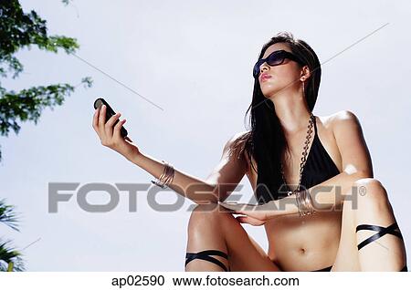 Woman in bikini, holding mobile phone View Large Photo Image Stock Image - Woman in bikini, holding mobile phone . Fotosearch